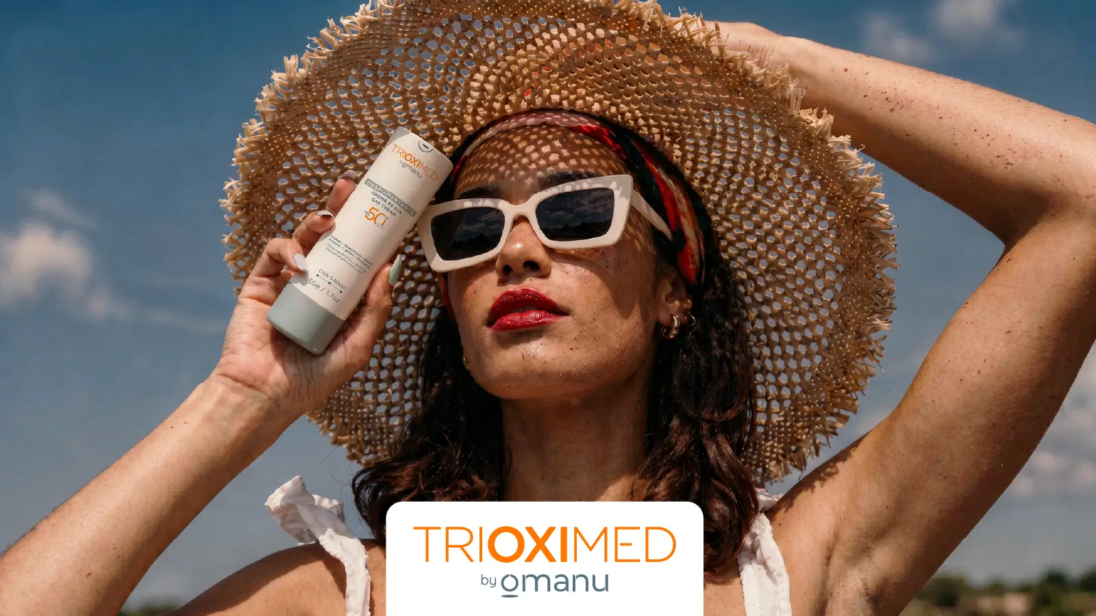 Mujer al aire libre usando sombrero y lentes de sol mientras sostiene la Crema de Día Despigmentante FPS 50+ de Trioximed para proteger la piel y prevenir manchas durante el verano.